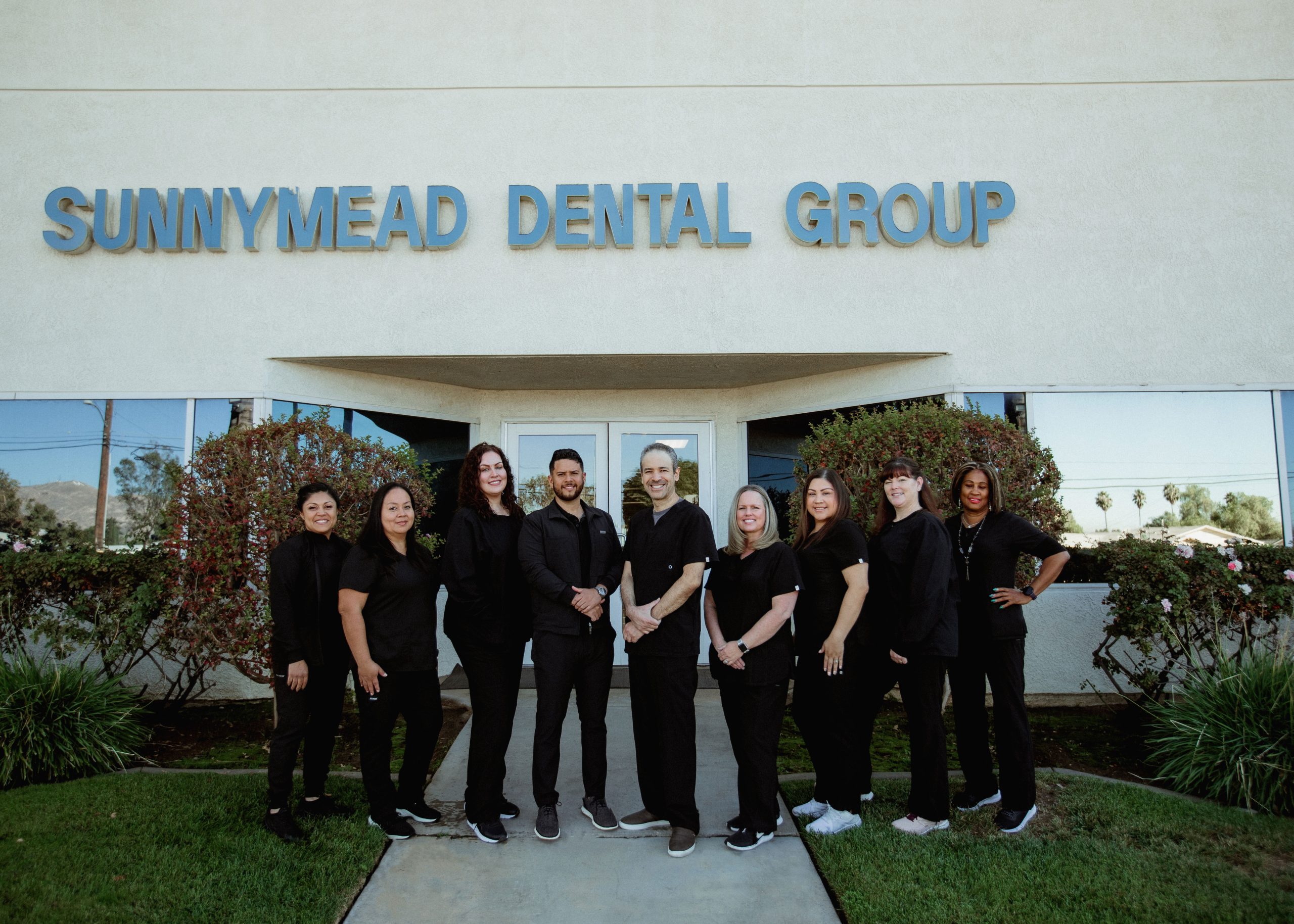 Team at Sunnymead Dental smiling in front of the dentist office